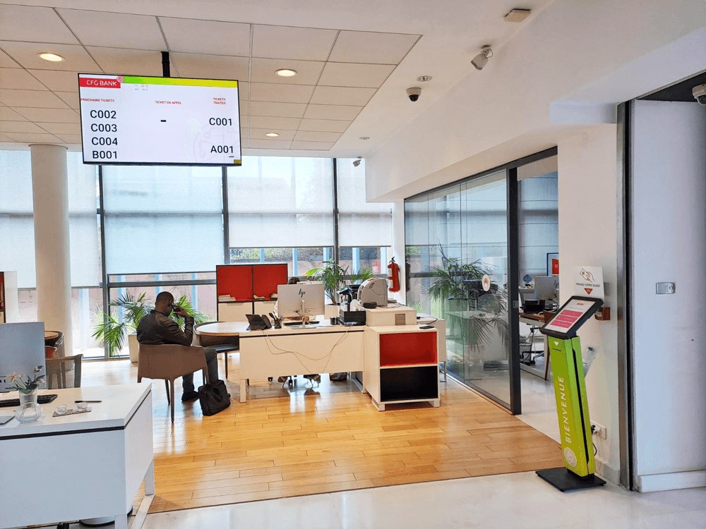 Staff assisting clients at service counters while Moviik’s queue management system displays active tickets.