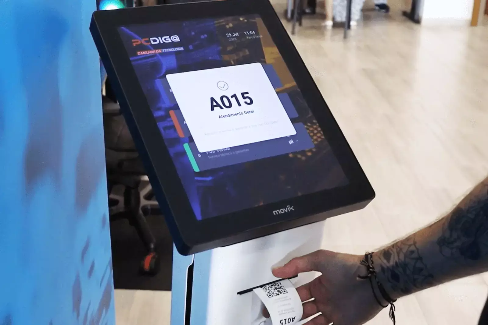 Customer using Moviik Tiik 15 kiosk to take a digital ticket in a retail store” Customer using Moviik Tiik 15 kiosk to take a digital ticket in a retail store”