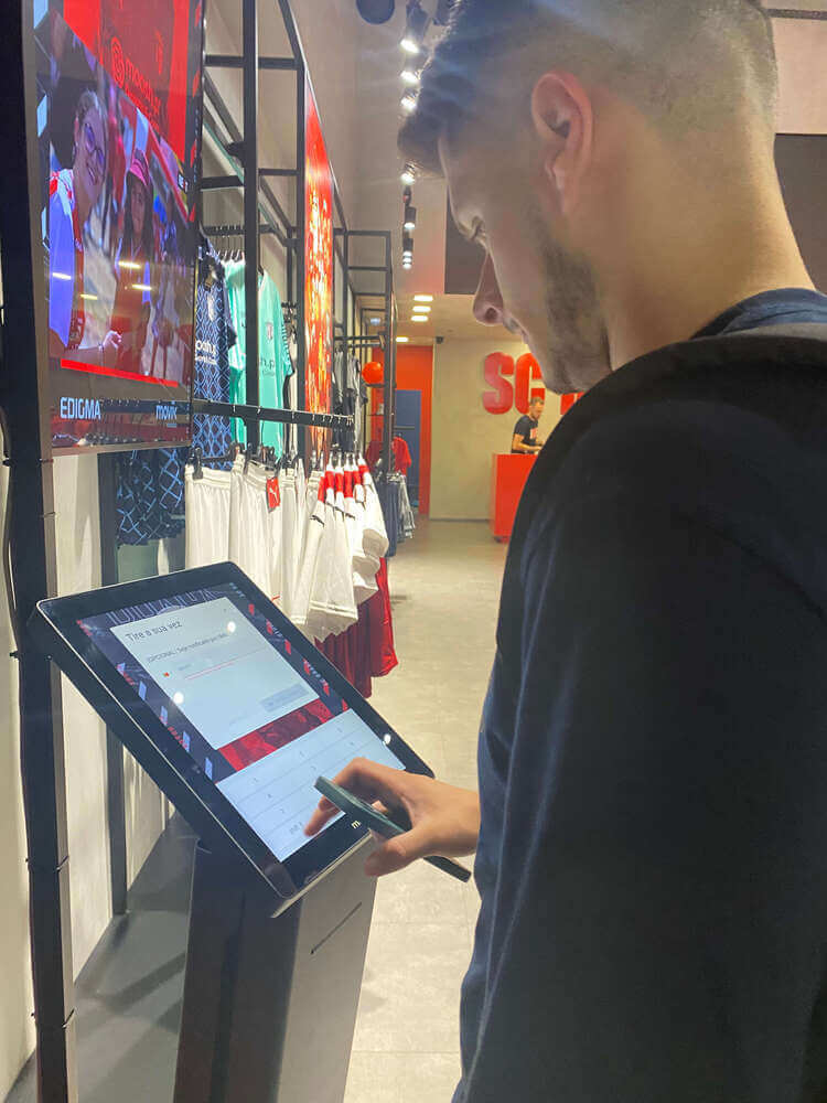 A fan using the kiosk to take a paper or SMS ticket at SC Braga official store.