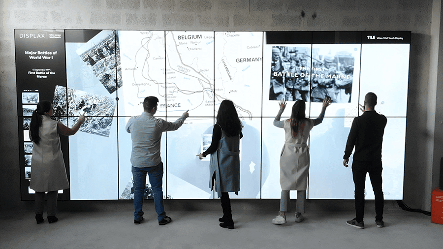 Visitors interacting simultaneously with the DISPLAX TILE Pro video wall in a public space.